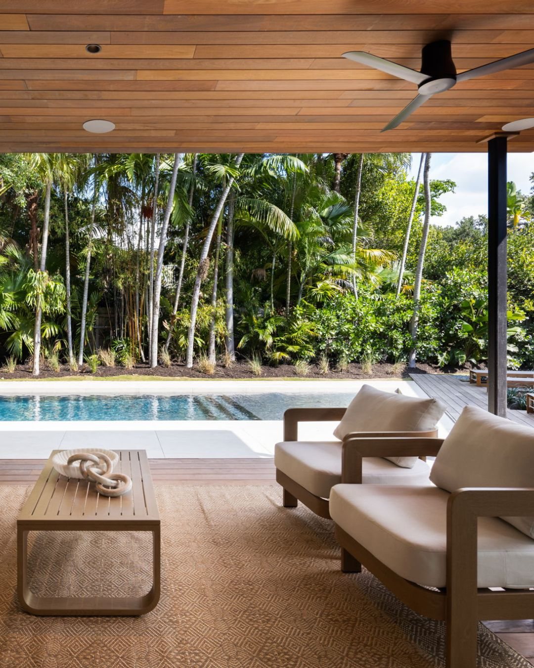 Covered terrace under a warm wood ceiling, looking out to the pool
